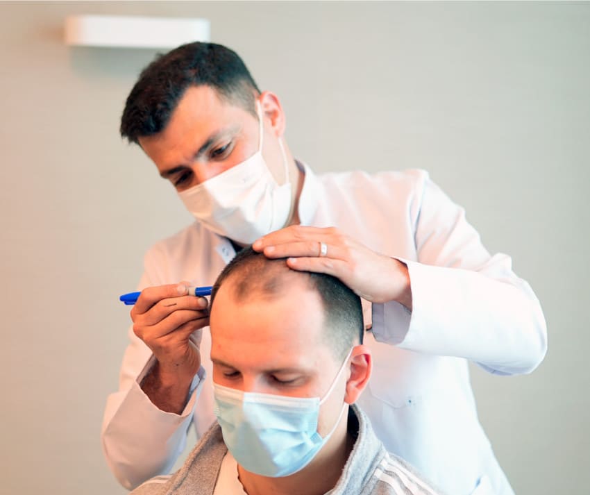 Dr Ibrahim drawing a hairline onto a patient's head