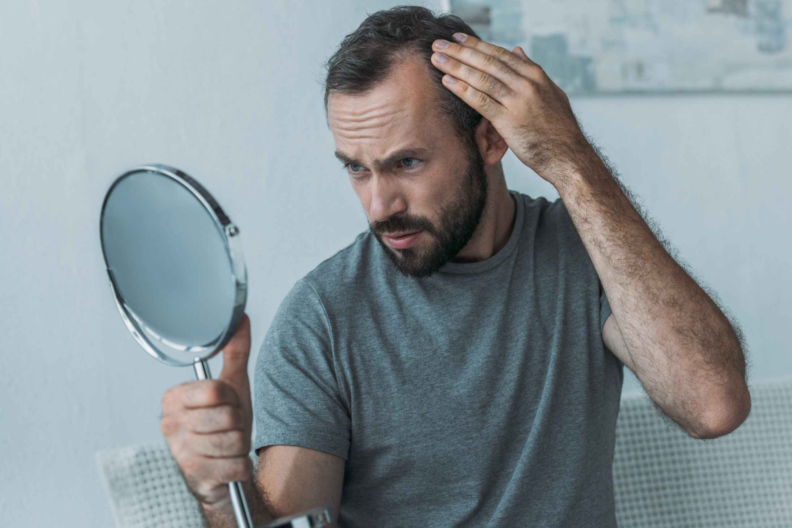 A man looking at his receding hairline in the mirror