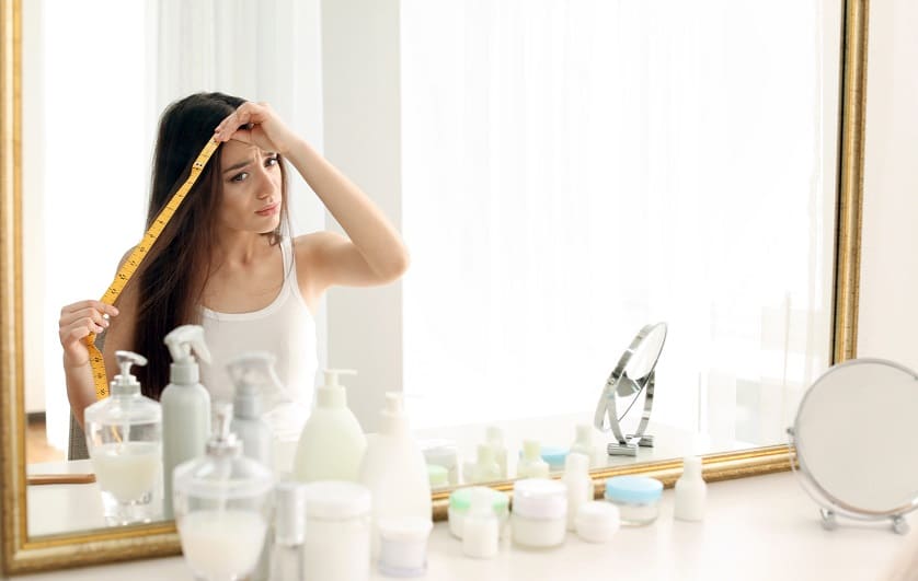 Mujer midiéndose el cabello frente a un espejo