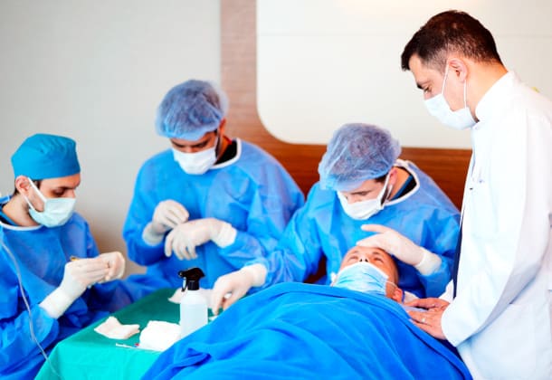 Médico y su equipo durante tratamiento con un paciente en la clínica de injerto capilar