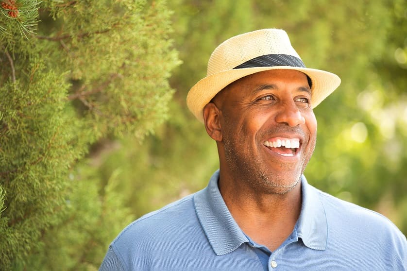 Lächelnder Mann trägt Hut nach der Haartransplantation