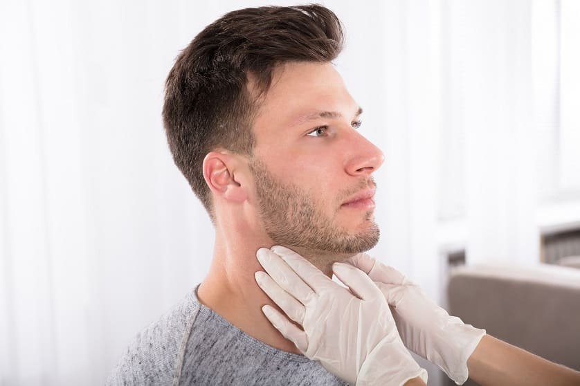 Arzt untersucht die Schilddrüse seines Patienten um die Ursache seiner Haarprobleme zu finden