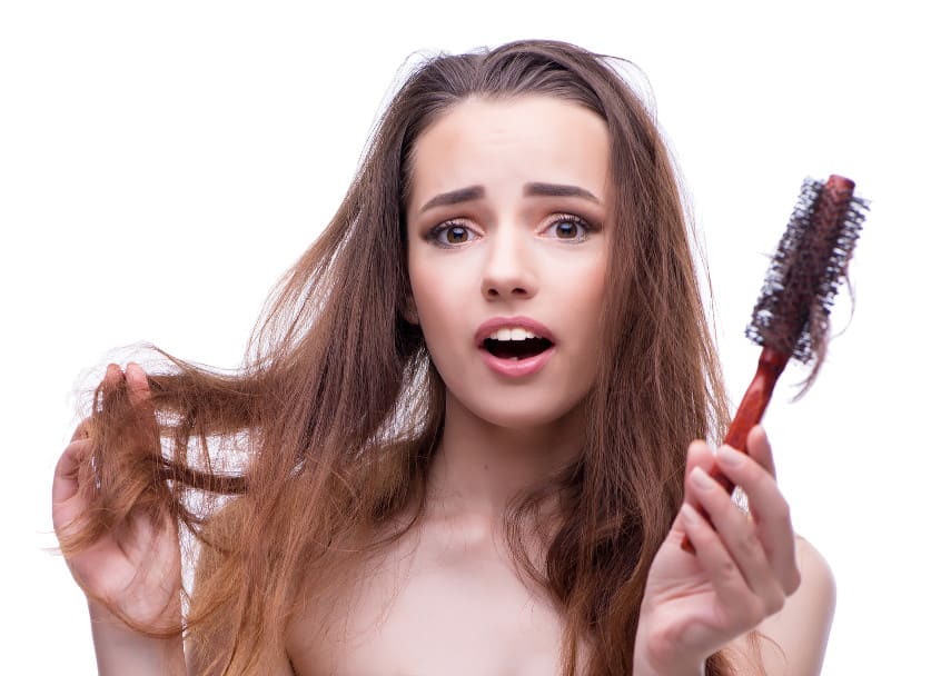 Entsetzte Frau in der rechten Hand ihre Haare und in der linken Hand eine Bürste mit ausgefallenen Haaren