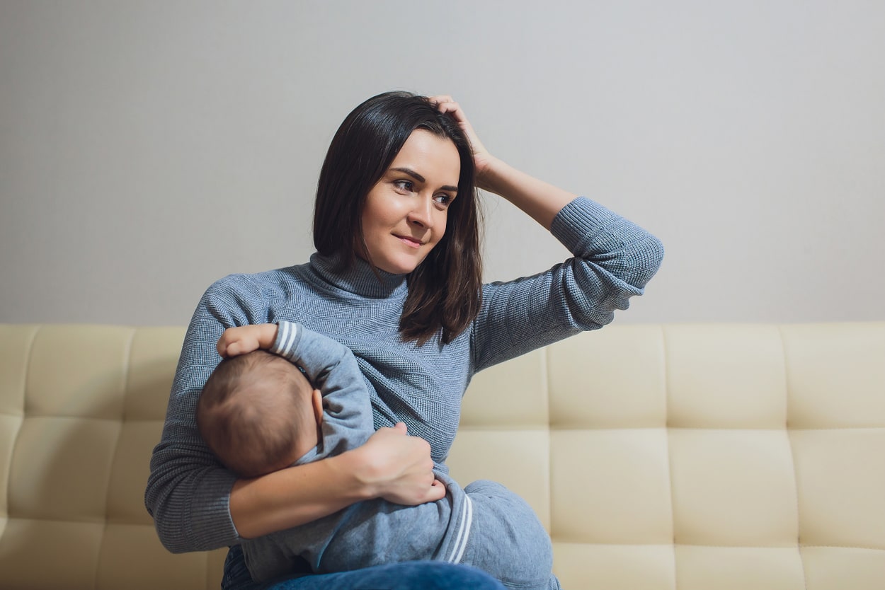 Frau hält Baby in der Hand und fässt sich an den Kopf