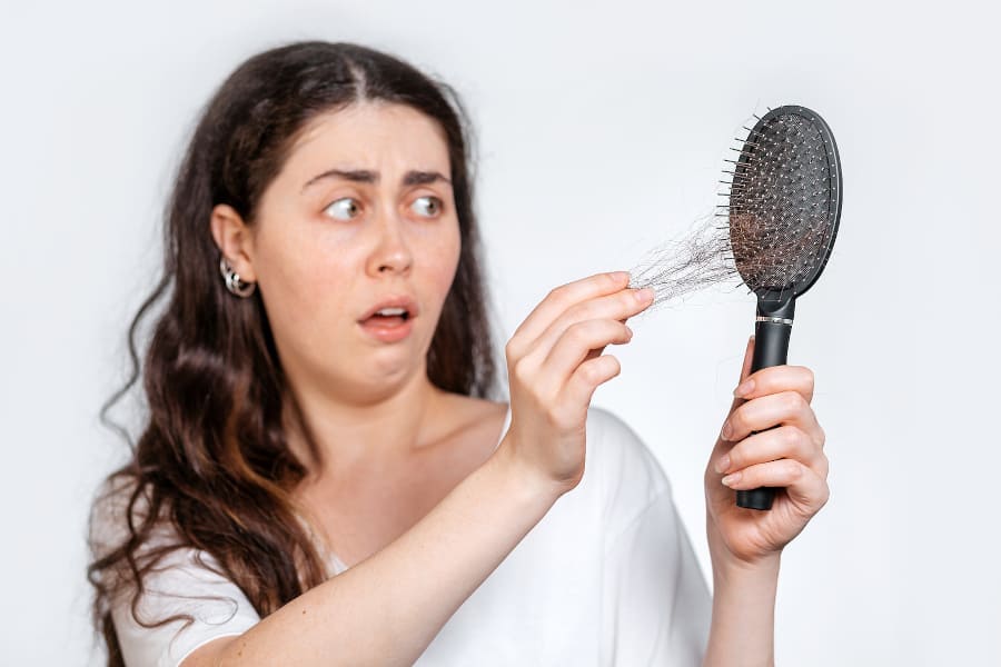 Frau zieht erschrocken aus ihrer Bürste ein büchel Haare