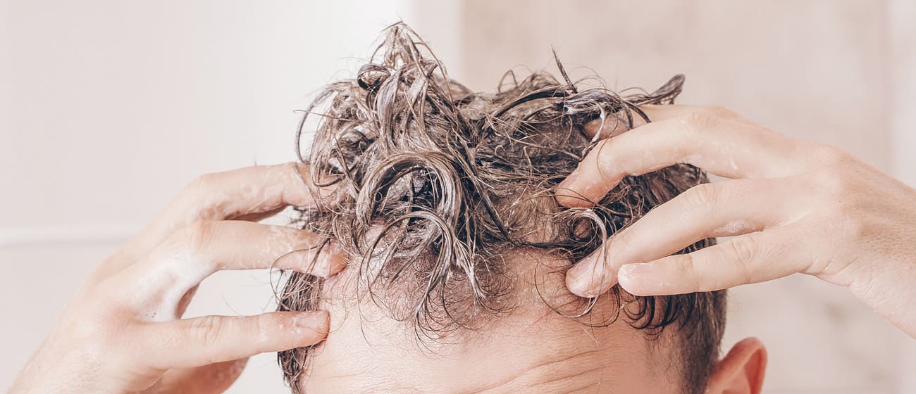 Mann shampooniert seine Haare