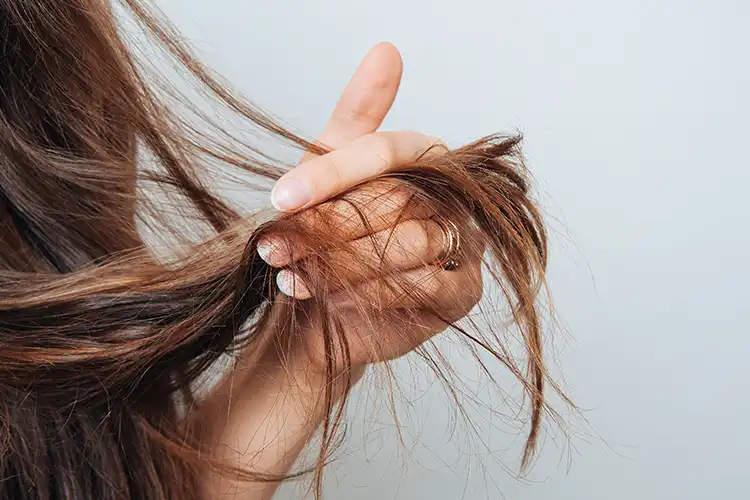Eine Frau hält ihre Haarspitzen zwischen den Fingern.