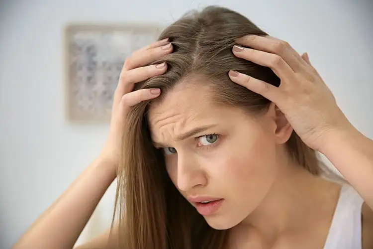 Eine Frau schaut besorgt den Haarverlust im Schläfenbereich an  